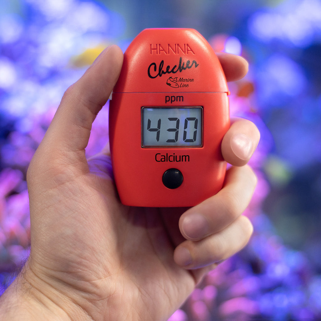 Hanna Checker HC HI758 marine calcium held in hand in front of a reef aquarium