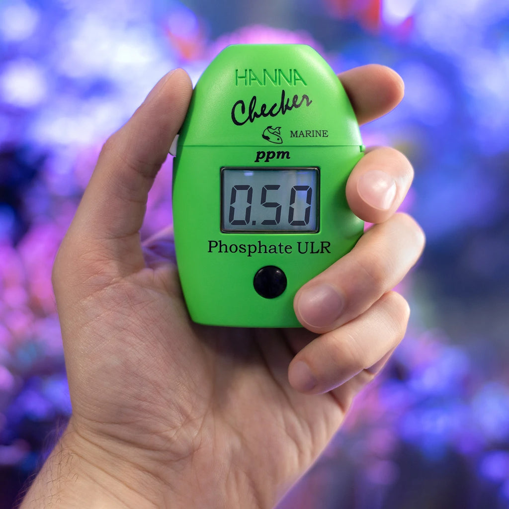 Hanna Checker HC HI774 phosphate ULR held in hand in front of a reef aquarium