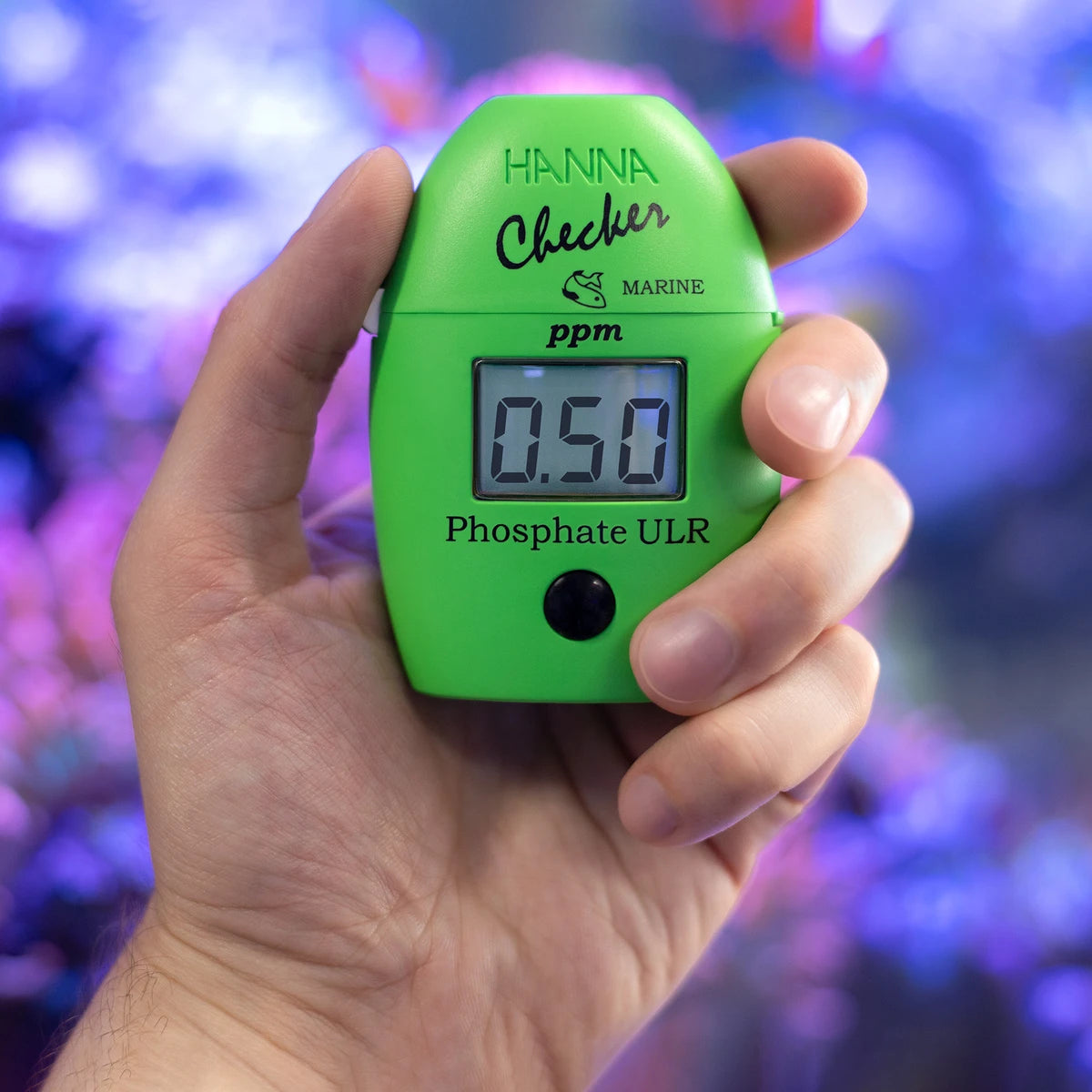 Hanna Checker HC HI774 phosphate ULR held in hand in front of a reef aquarium
