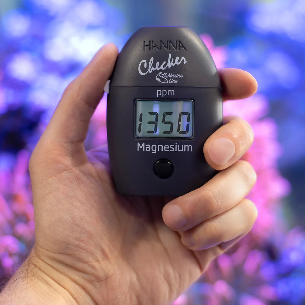 Hanna Checker HC HI783 marine magnesium held in hand in front of a reef aquarium
